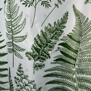 May include: White fabric with a green fern pattern. The ferns are printed in a dark green color and are arranged in a random pattern.