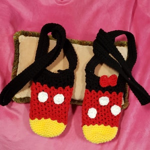May include: A pair of crocheted Mickey Mouse slippers with black straps. The slippers are red, yellow, and white with black polka dots.
