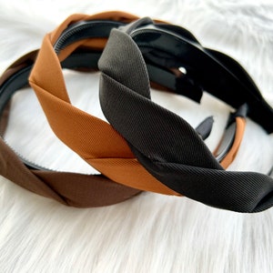 May include: Three braided headbands in brown, black, and tan colors. The headbands are made of a soft, stretchy fabric and have a simple, elegant design.