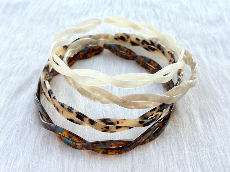 Puede incluir: Tres diademas de pl&aacute;stico trenzadas en diferentes patrones. Una es blanca, otra es marr&oacute;n con estampado de leopardo y la &uacute;ltima es marr&oacute;n con un patr&oacute;n azul y blanco.