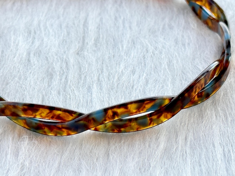 Puede incluir: Una diadema de carey marr&oacute;n y azul con un dise&ntilde;o trenzado.