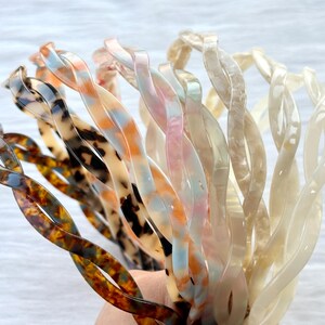 Puede incluir: Un conjunto de ocho diademas de pl&aacute;stico retorcidas en varios colores y patrones, incluyendo marr&oacute;n carey, azul y blanco remolino y blanco.