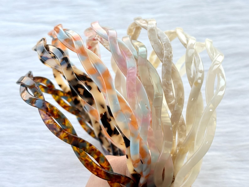Puede incluir: Un conjunto de ocho diademas de pl&aacute;stico retorcidas en varios colores y patrones, incluyendo marr&oacute;n carey, azul y blanco remolino y blanco.