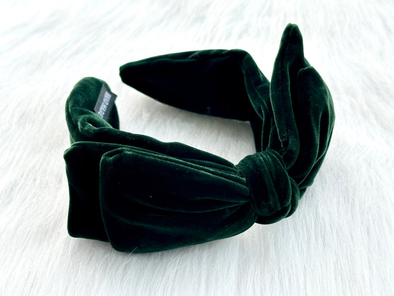 Puede incluir: Diadema de terciopelo verde oscuro con un lazo anudado. La diadema est&aacute; hecha de un material suave y afelpado. La etiqueta dice "HAND MADE". Un accesorio para el cabello.