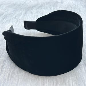 Pode incluir: Uma faixa de cabeça de veludo preto. A faixa de cabeça é larga e tem um design simples.