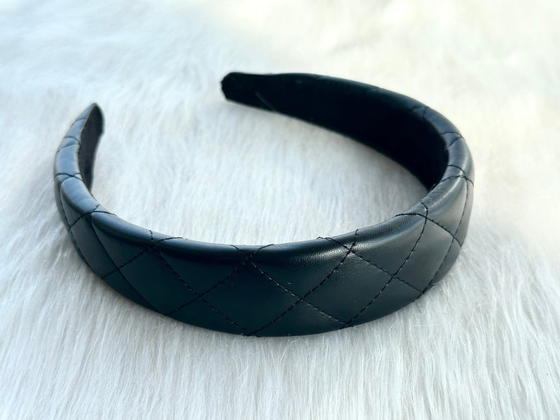 May include: A black quilted headband. The headband is made of a soft, faux leather material and has a classic quilted design.