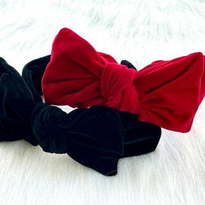 Puede incluir: Dos diademas de terciopelo con grandes lazos. Una es de color rojo intenso, la otra verde oscuro. Las diademas est&aacute;n sobre un fondo blanco y esponjoso. Estos accesorios son adecuados para diversas ocasiones.