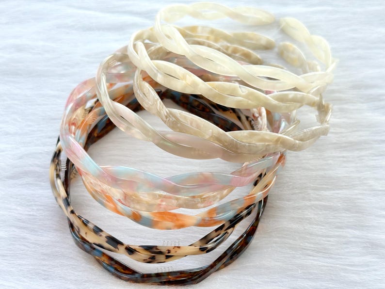 Puede incluir: Un conjunto de seis diademas de pl&aacute;stico trenzadas en varios colores y patrones, incluyendo blanco, marr&oacute;n y rosa.