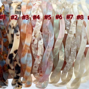 Puede incluir: Nueve diademas trenzadas de pl&aacute;stico para el cabello en varios colores y patrones, incluyendo carey, marr&oacute;n, blanco e iridiscente. Las diademas est&aacute;n numeradas del 1 al 9.