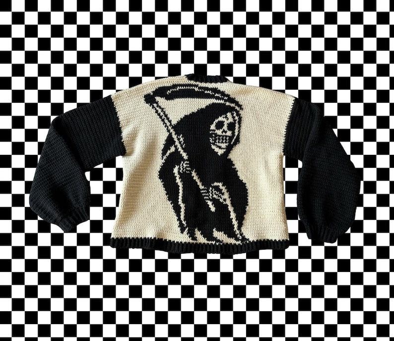 May include: A white knitted sweater with black sleeves and a black and white graphic of a skeleton holding a scythe on the front.