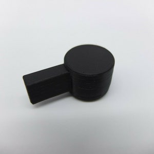 May include: A black plastic 3D printed object with a round top and a rectangular base.
