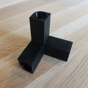 Può includere: Connettore d'angolo in plastica nera con tre lati e tre fori. Il connettore è progettato per unire tre pezzi di tubo o tubatura.