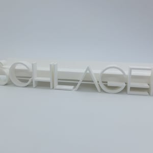 Op de afbeelding: Witte 3D-geprinte letters die het woord "SCHLAGER" spellen.