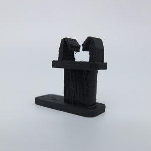 May include: Black plastic cable clip with two prongs for holding wires or cables in place.