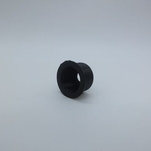 Op de afbeelding: Een zwarte plastic ring met een gat in het midden. De ring heeft een diameter van ongeveer 2,5 cm.