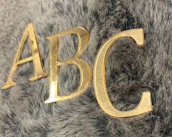 May include: Gold-colored letters spelling out "ABC" on a gray fuzzy background.