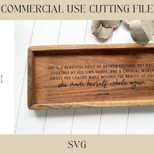 Puede incluir: Una bandeja de madera con una cita sobre cerámica rota y autocuración. La cita dice: "Ella es una hermosa pieza de cerámica rota, vuelta a unir por sus propias manos. Y un mundo crítico juzga sus grietas mientras se pierde la belleza de cómo se hizo entera de nuevo." La cita se atribuye a JMSTORM.