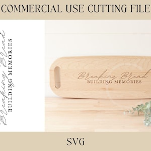 May include: A wooden cutting board with the text "Breaking Bread Building Memories" engraved on it. The board has a handle on each end.