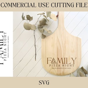 Pu&ograve; includere: Un tagliere di legno con la scritta "Family Pizza Night Where Memories Are Made" incisa su di esso. Il tagliere &egrave; di colore marrone chiaro e ha un manico. Ci sono foglie verdi sulla superficie dietro il tagliere.