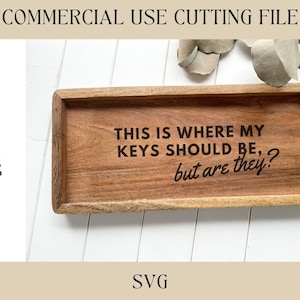 May include: A wooden tray with the text "This is where my keys should be, but are they?" engraved on it. The tray is sitting on a white surface.