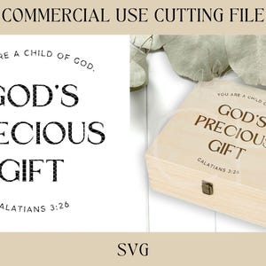 Puede incluir: Una caja de madera con el texto "You are a child of God. God's Precious Gift Galatians 3:26" grabado en la parte superior. La caja está sobre una superficie blanca.