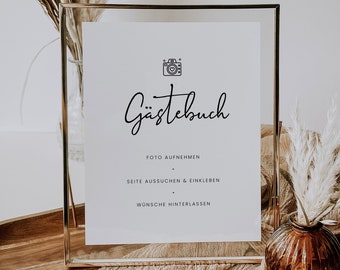 May include: A gold-framed sign with the text "Gästebuch" in black cursive script. The sign also includes instructions for guests to take a photo, choose a page, and leave a message.