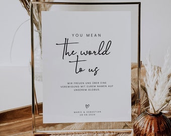 Puede incluir: Un cartel blanco en un marco dorado con el texto "You mean the world to us" y el texto "Wir freuen uns über eine Verewigung mit eurem Namen auf unserem Globus."  El cartel también incluye el texto "Marie & Sebastian 28-08-2026".