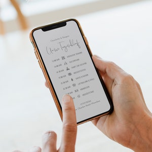 Könnte beinhalten: Ein Smartphone-Bildschirm zeigt einen Hochzeitstagsplan mit Symbolen und Uhrzeiten. Der Plan beinhaltet Ereignisse wie die Trauung, den Empfang und das Abendessen. Das Datum ist der 17. Juli 2026 und der Ort ist das Charles Hotel in München.