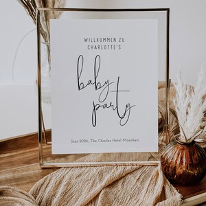 Puede incluir: Un cartel enmarcado en dorado con el texto "Willkommen zu Charlotte's Baby Party" y la fecha "Juni 2026, The Charles Hotel Munchen".