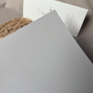 May include: A light gray textured card with a subtle linen finish. The card is blank and ready for writing.