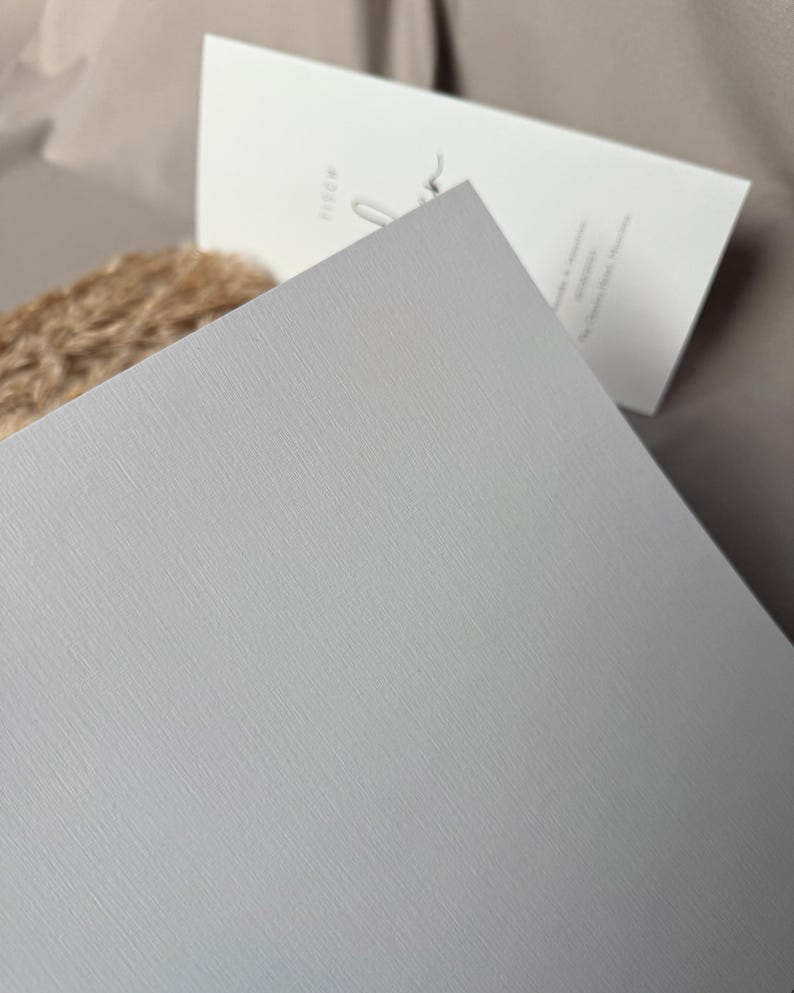 May include: A light gray textured card with a subtle linen finish. The card is blank and ready for writing.