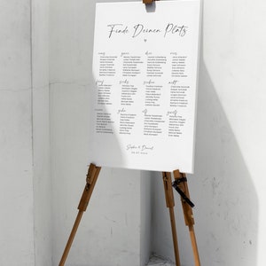 May include: A white sign with black text on an easel. The sign says "Finde Deinen Platz" and lists names under the headings "eins", "zwei", "drei", "vier", "f&uuml;nf", "sechs", "sieben", "acht", "neun", "zehn", "elf", "zw&ouml;lf". The sign is dated "20-07-20xx".