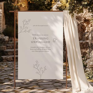 May include: A wedding sign with the text "TRAUUNG UNPLUGGED" in German, displayed on a copper-colored metal stand. The sign is cream-colored with floral branch illustrations. The sign encourages guests to enjoy the moment offline.