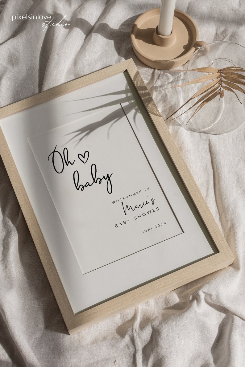 Puede incluir: Una impresi&oacute;n enmarcada con el texto "Oh baby" y un s&iacute;mbolo de coraz&oacute;n. Debajo del texto se lee "Willkommen zu Marie's Baby Shower Juni 2026".