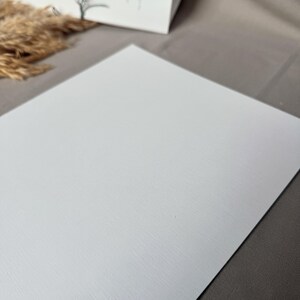 May include: A white textured sheet of paper. The paper has a subtle, fine grain texture.