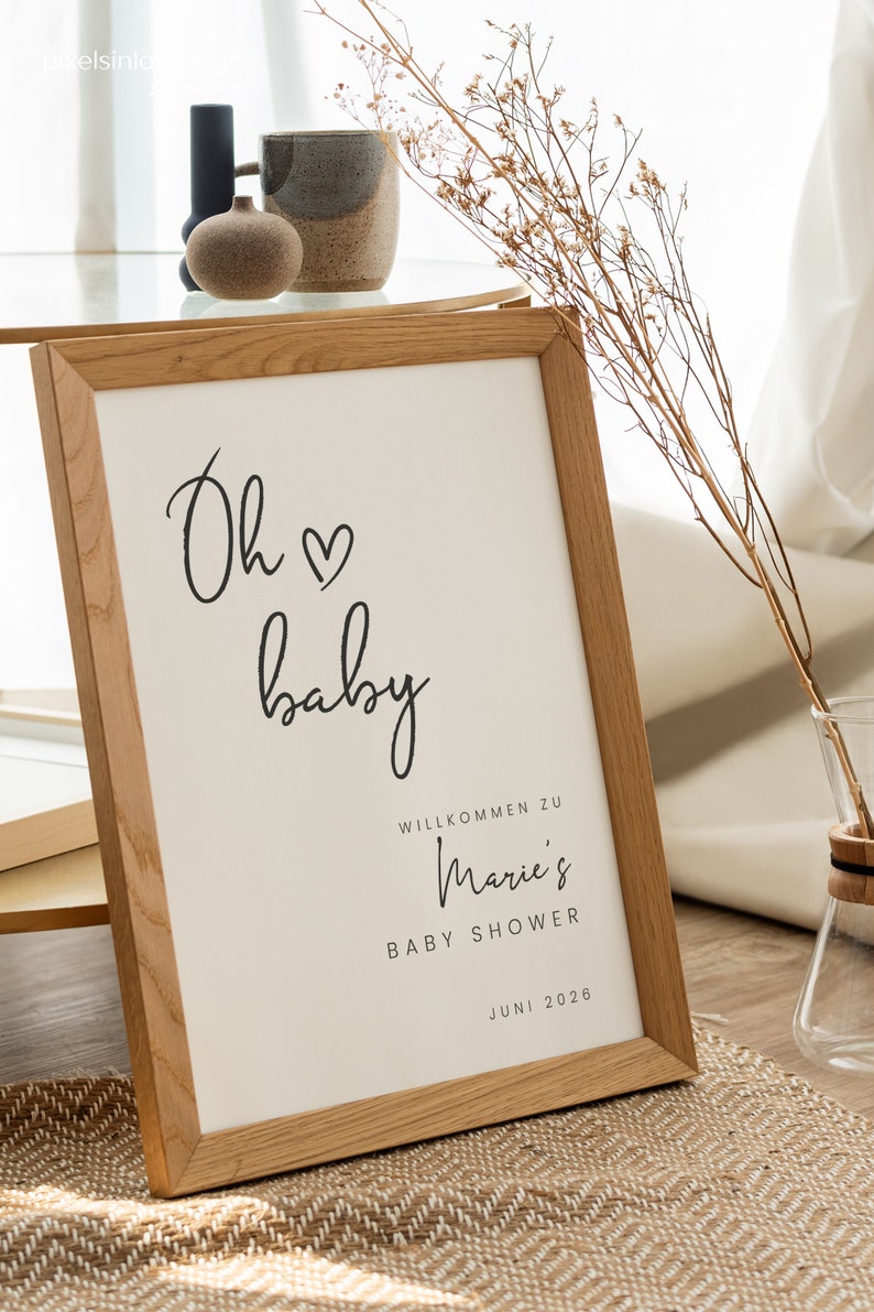Puede incluir: Un cartel enmarcado con el texto "Oh baby" en letra cursiva con un s&iacute;mbolo de coraz&oacute;n. El cartel tambi&eacute;n incluye el texto "Willkommen zu Marie's Baby Shower Juni 2026".