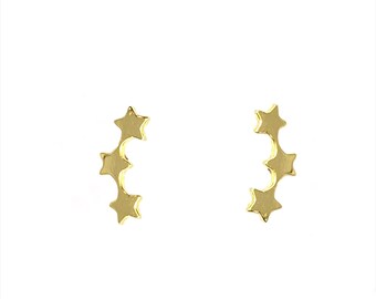 May include: A pair of gold star shaped earrings. Each earring has four stars arranged in a curved line.