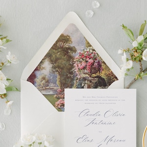 May include: A wedding invitation suite featuring a white invitation card with elegant calligraphy and a matching envelope. The envelope interior displays a landscape painting. Cherry blossoms and a small plate with stamps complete the scene.