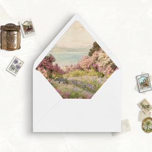 May include: A white envelope with a landscape scene inside, featuring a lake and colorful flowers. Decorative stamps and a small mailbox are scattered around the envelope, creating a vintage aesthetic.