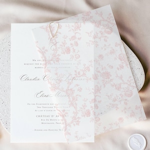 Op de afbeelding: Een witte huwelijksuitnodiging met een roze bloemenpatroon eroverheen. De uitnodiging bevat de namen Claudia en Elias, de datum en de locatie Chateau D'Amboise.