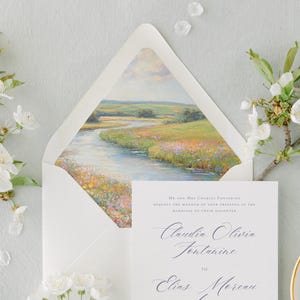 May include: A white envelope with a watercolor painting of a river flowing through a field. The envelope is open and the painting is visible. The text on the invitation reads "Mr. and Mrs. Charles Fontaine request the honour of your presence at the marriage of their daughter Claudia Olivia Fontaine to Elias Moreau."
