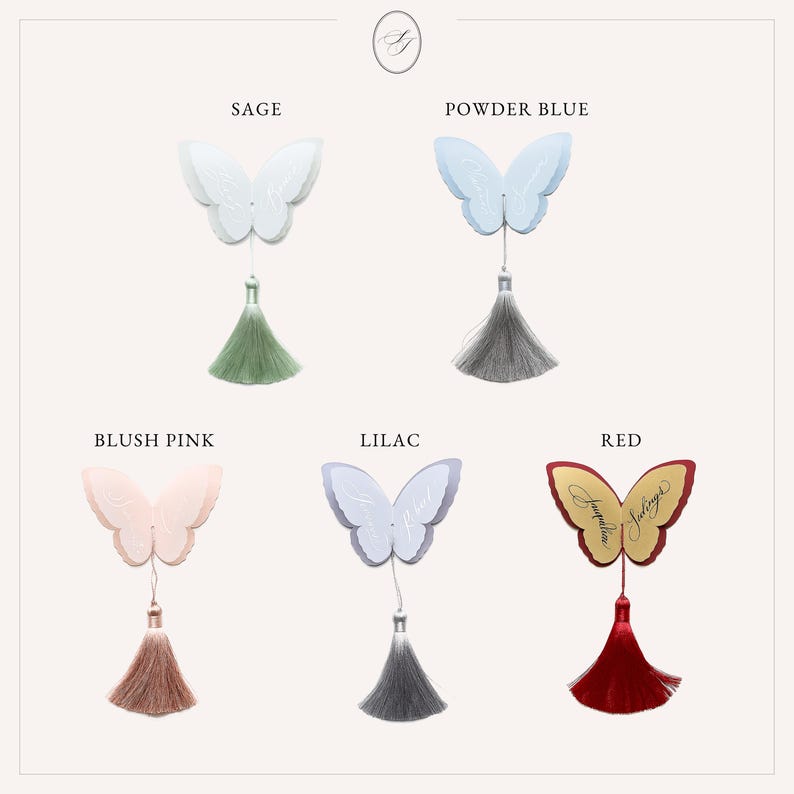 May include: A collection of butterfly-shaped ornaments in various colors: sage, powder blue, blush pink, lilac, and red. Each butterfly has a tassel hanging below. The word "Jacqueline" is written on the red butterfly.