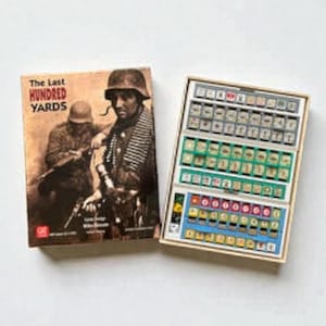 Può includere: Una scatola di gioco da tavolo e pedine. La scatola ha il titolo "The Last Hundred Yards" con un'immagine di soldati. Le pedine sono in un vassoio di legno con vari componenti colorati ed etichettati.