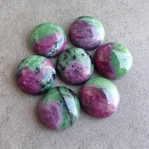 May include: Six polished, circular cabochons of ruby zoisite stone, each displaying a distinct blend of vibrant magenta-pink ruby inclusions set within a mottled, mossy green zoisite matrix, featuring smooth, rounded surfaces and glossy finishes.