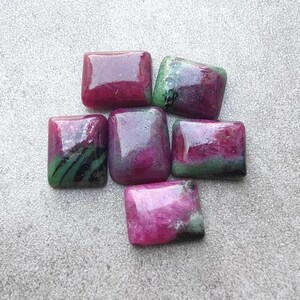 May include: Six polished, rectangular cabochons featuring a vibrant mix of deep magenta, pink, and dark green mineral inclusions. Each stone displays a smooth, glossy surface with unique color patterns and natural variations in the stone texture.