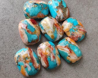 May include: A collection of eight polished stones with a turquoise base color, accented with orange, red, and gold veining. The stones have an irregular, rounded shape and are displayed on a gray surface.