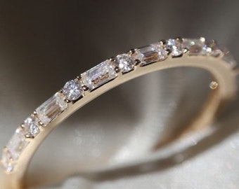 May include: A delicate gold band ring with a row of small, clear, rectangular and round-shaped gemstones.