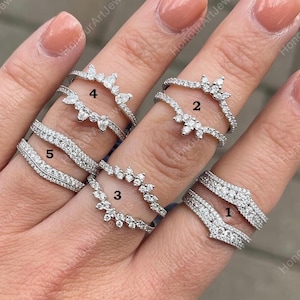Może przedstawiać: Pięć srebrnych pierścionków z przezroczystymi kamieniami z cyrkonii sześciennej. Pierścionki są ponumerowane od 1 do 5. Pierścionki są zaprojektowane do noszenia razem, z większymi pierścionkami na mniejszych.