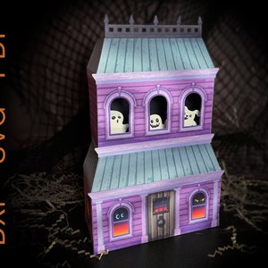 May include: A purple and blue papercraft haunted house with windows and a door. The windows have ghosts and a dog peeking out. The door has a black door knocker and a red and orange glow coming from the windows.
