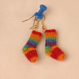 May include: Rainbow striped knitted sock earrings. The socks are red, orange, yellow, green, blue, purple, and pink. The earrings are made with gold hooks.